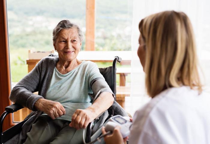 Elderly woman in wheelchair with carer